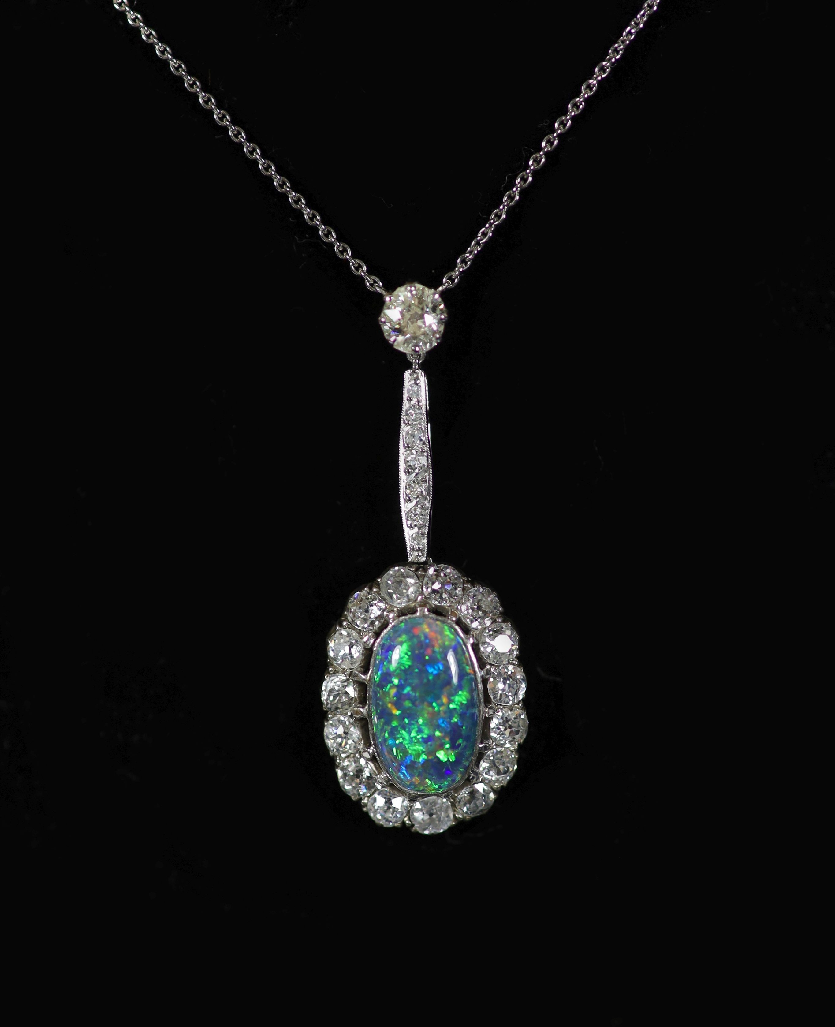 An early 20th century white gold, oval black opal and diamond cluster set drop pendant necklace
